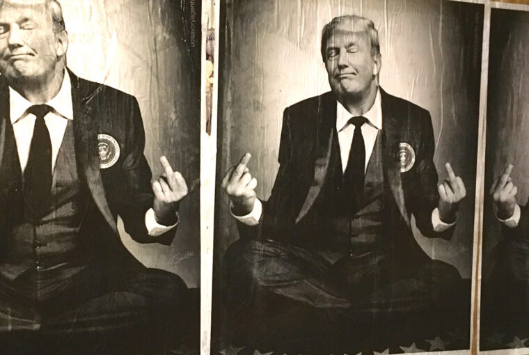 A man in suit and tie sitting on the ground.