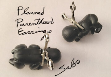 A pair of black plastic hippo earrings with scissors.