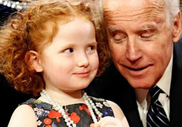A little girl and an older man are smiling.