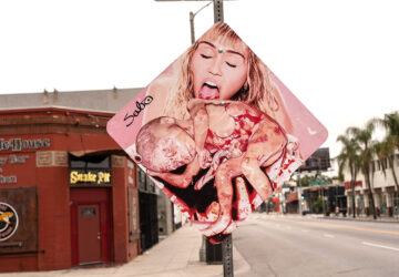 A sign with a picture of miley cyrus holding a baby.
