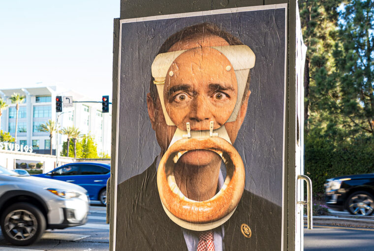 A poster of president obama with a bagel in his mouth.