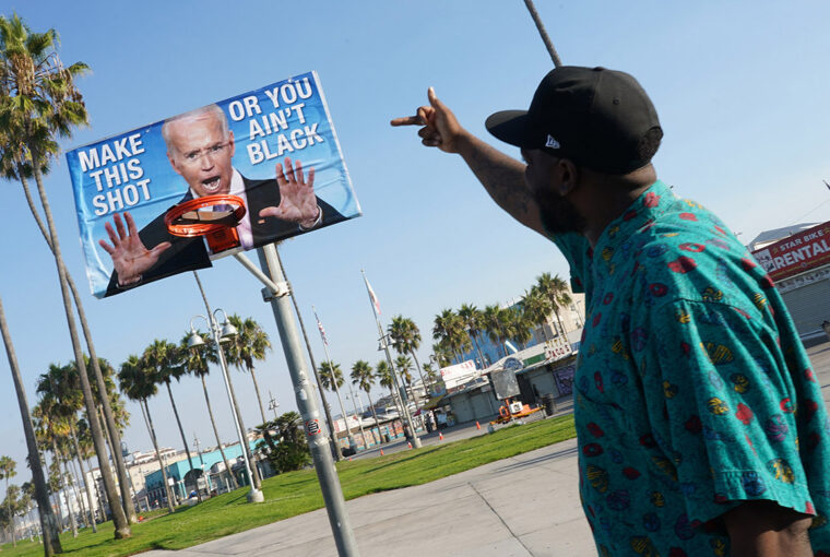 A man pointing to an image of joe biden.