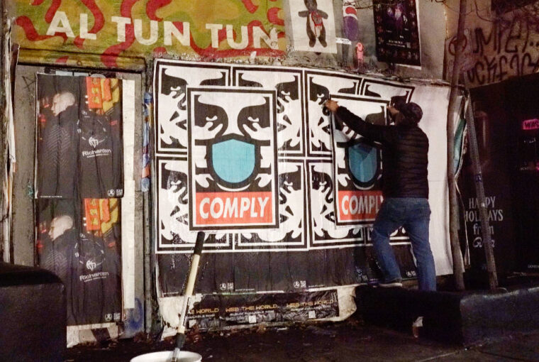 A man is putting up posters on the wall